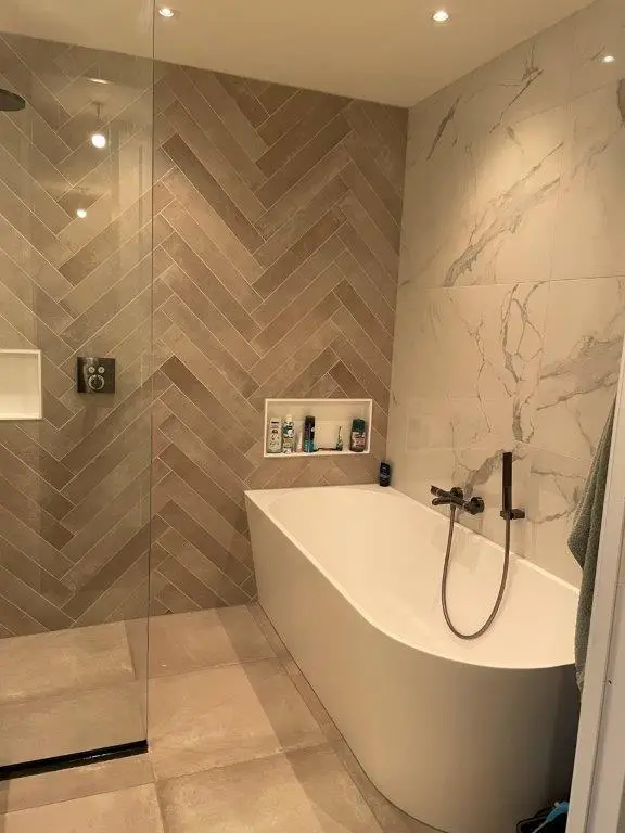 Exclusieve design badkamer ontwerp door LucasBouwt. Half vrijstaand bad met visgraad tegels op de wand